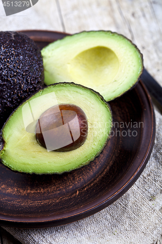 Image of Fresh organic avocado on ceramic plate and linen napkin on rusti