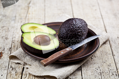 Image of Fresh organic avocado on ceramic plate and knife on  linen napki