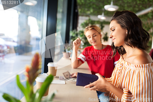 Image of female friends paying for coffee at cafe