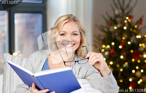 Image of woman with glasses and book on christmas at home