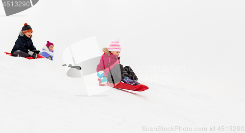 Image of kids sliding on sleds down snow hill in winter