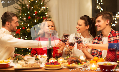 Image of happy friends drinking red wine at christmas party