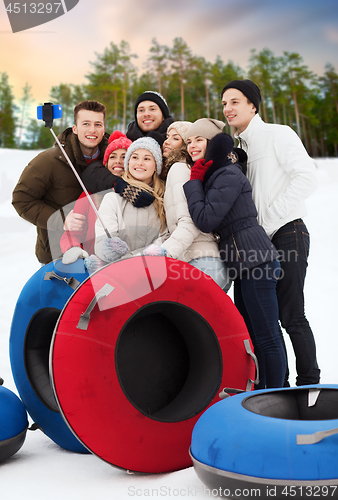 Image of friends with snow tubes taking selfie in winter