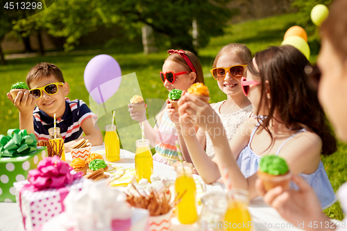 Image of kids eating cupcakes on birthday party in summer
