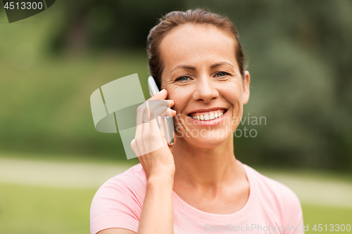 Image of happy woman calling on smartphone at summer park