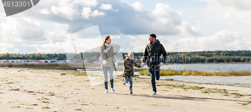 Image of happy family running along autumn beach