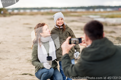 Image of family photographing by smartphone on autumn beach