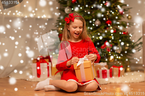 Image of smiling girl with christmas gift at home