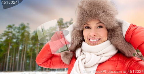 Image of happy woman in fur hat over winter forest