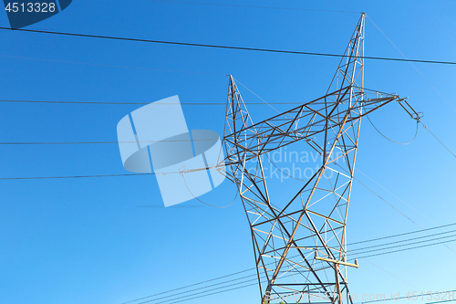 Image of transmission tower and power line over blue sky