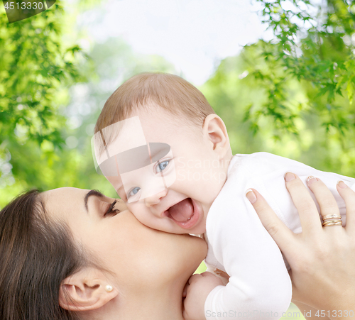 Image of mother kissing baby over green natural background