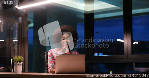 Image of black businesswoman using a laptop in night startup office