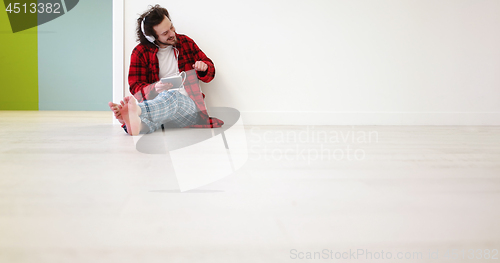 Image of young man listenig music on tablet at home