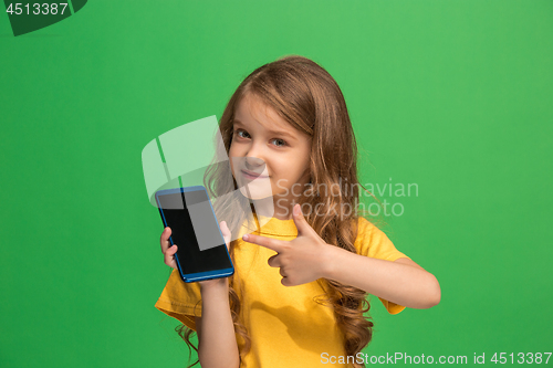 Image of The happy teen girl standing and smiling against green background.