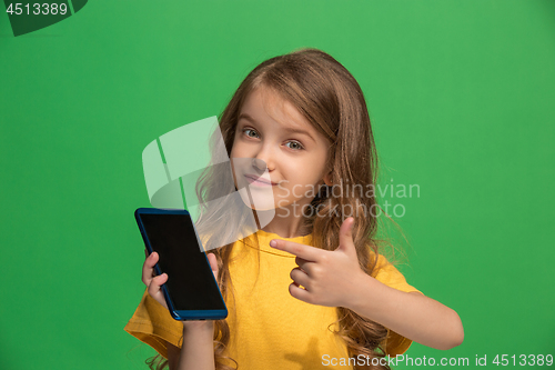 Image of The happy teen girl standing and smiling against green background.