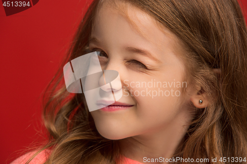 Image of The happy teen girl standing and smiling against red background.