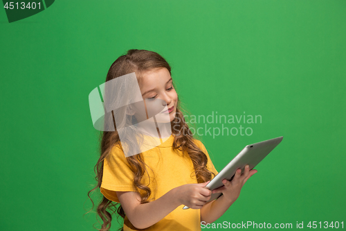 Image of Little funny girl with tablet on green background