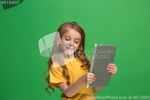 Image of Little funny girl with tablet on green background