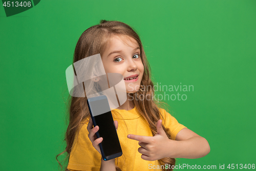 Image of The happy teen girl standing and smiling against green background.