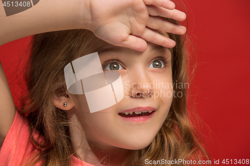 Image of The happy teen girl standing and smiling against red background.