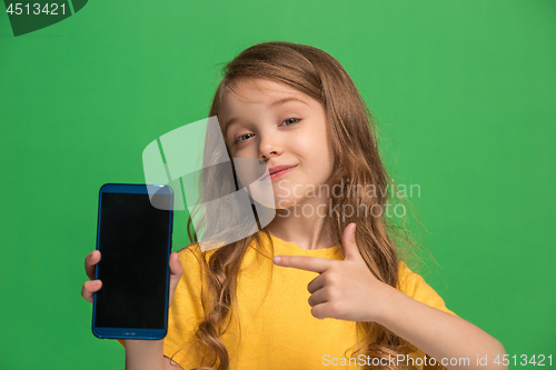 Image of The happy teen girl standing and smiling against green background.