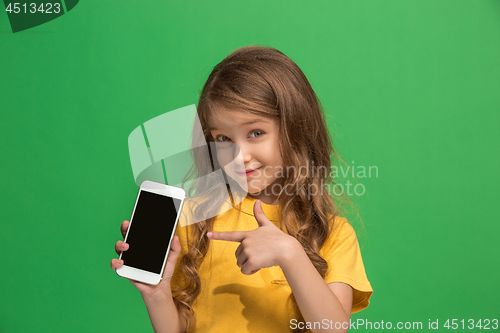 Image of The happy teen girl standing and smiling against green background.