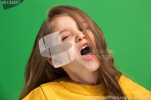Image of The happy teen girl standing and smiling against green background.