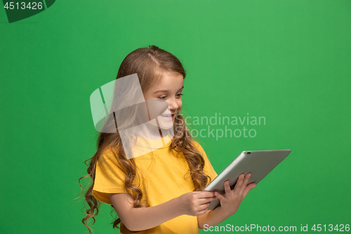 Image of Little funny girl with tablet on green background