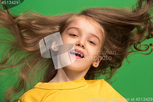 Image of The happy teen girl standing and smiling against green background.