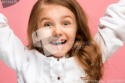 Image of The happy teen girl standing and smiling against pink background.