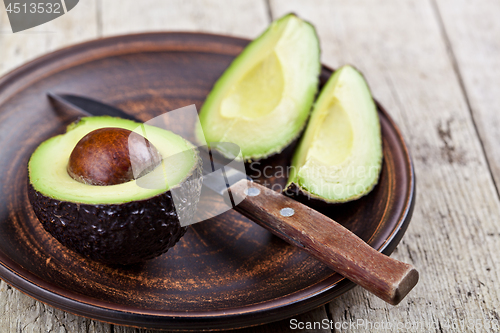 Image of Fresh organic avocado on ceramic plate and knife on rustic woode