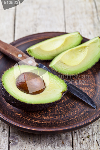 Image of Fresh organic avocado on ceramic plate and knife on rustic woode