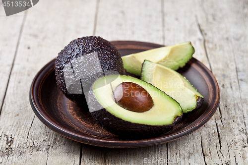 Image of Fresh organic avocado on ceramic plate on rustic wooden table ba