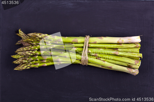 Image of Bunch of fresh raw garden asparagus on black board background. G
