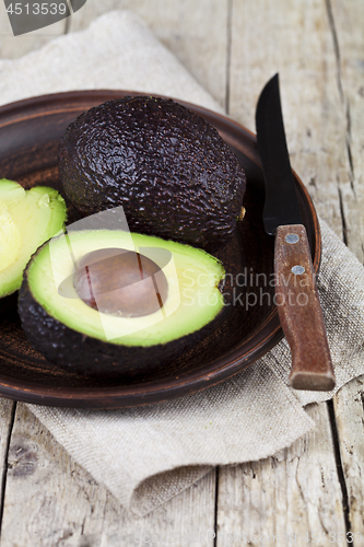 Image of Fresh organic avocado on ceramic plate and knife on  linen napki