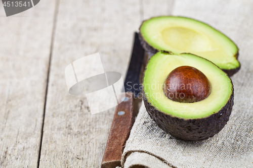 Image of Avocado and knife on linen napkin old wooden table background. F