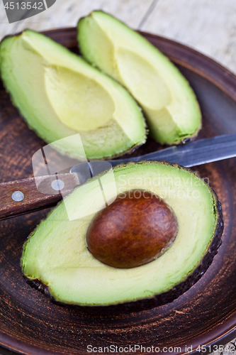 Image of Fresh organic avocado on ceramic plate and knife on rustic woode