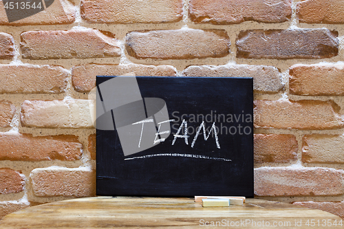 Image of Blackboard with the word "Team" drown by hand on wooden table on