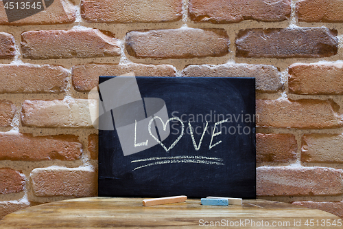 Image of Black board with the word "Love" drown by hand on wooden table o