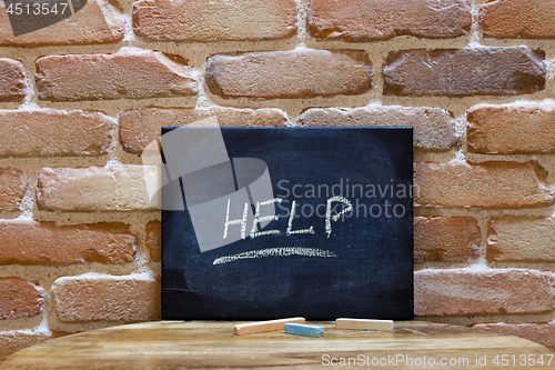 Image of Blackboard with the word "Help" drown by hand on wooden table on