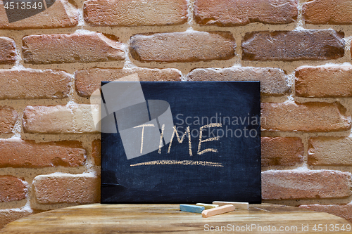 Image of Black board with the word "Time" drown by hand on wooden table o