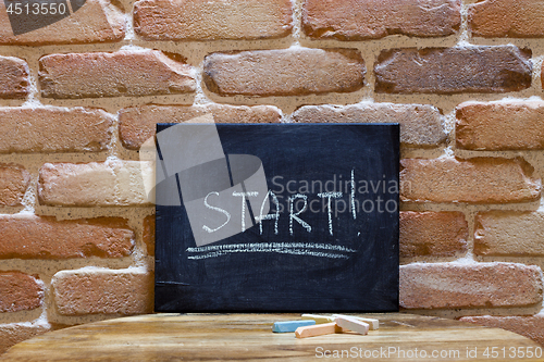 Image of Black board with the word "Start!" drown by hand on wooden table