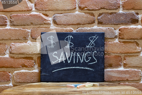 Image of Black board with the word "Savings" drown by hand on wooden tabl