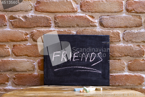 Image of Black board with the word FRIENDS drown by hand on wooden table 