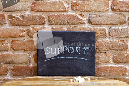 Image of Black board with the word SUPPORT drown by hand on wooden table 