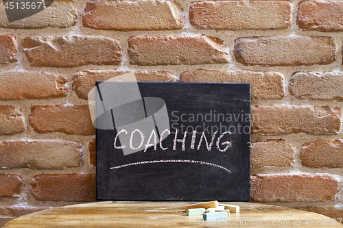 Image of Chalk board with the word COACHING drown by hand on wooden table