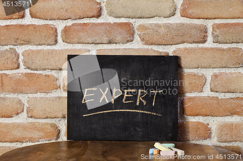 Image of Chalk board with the word EXPERT drown by hand on wooden table o