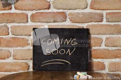 Image of Black board with the phrase COMING SOON drown by hand on wooden 