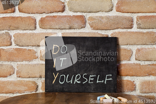 Image of Black chalkboard with the phrase DO IT YOURSELF drown by hand on