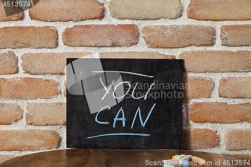 Image of Black board with the phrase YOU CAN drown by hand on wooden tabl